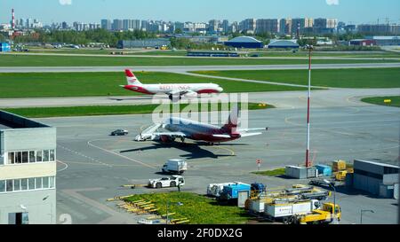 Das Flugzeug des Luftfahrtunternehmens steht auf einem Flugplatz des Int-Flughafens Pulkowo, St. Petersburg, Russland, während das Flugzeug der Red Wings abhebt. Stockfoto