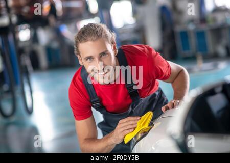 Glücklicher Mann wischen Auto mit Serviette. Stockfoto