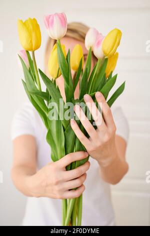 Junge Frau mit einem Blumenstrauß von festlichen Tulpen im Frühling Ihre Hände Stockfoto
