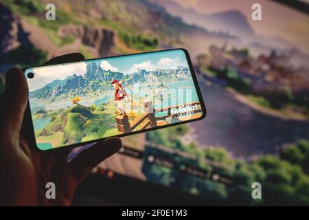 SWANSEA, Großbritannien - 4. MÄRZ 2021: Genshin Auswirkungen mobile Spiel auf Smartphone, beliebte App. Gameplay, Charakter, Logo auf dem Bildschirm angezeigt. Stockfoto