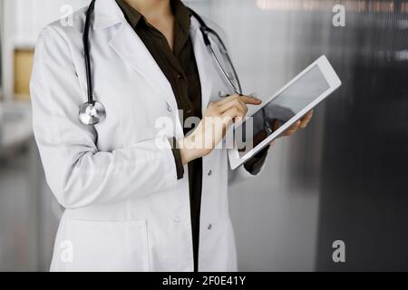 Unbekannter weiblicher Arzt mit Tablet-Computer in der Klinik. Perfekter medizinischer Service im Krankenhaus. Medizinkonzept Stockfoto