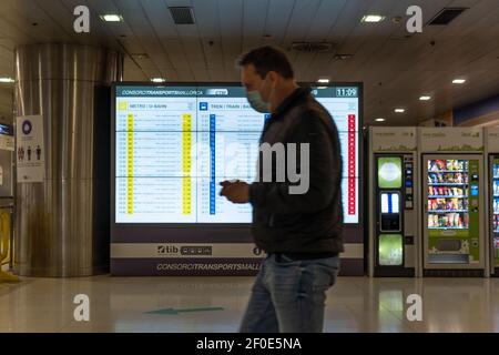 Palma de Mallorca, Spanien; märz 04 2021: Plaza de España Intermodal Station. Personen mit Gesichtsmaske, die mit den s vor der beleuchteten Tafel laufen Stockfoto