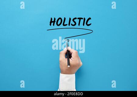 Geschäftsmann Hand schreiben das Business Buzzword holistic auf blauem Hintergrund. Ganzheitlicher Ansatz im Geschäftskonzept. Stockfoto