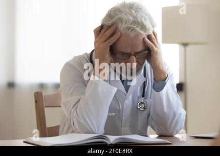 Unglücklicher Oberarzt leidet unter Kopfschmerzen in der Klinik Stockfoto