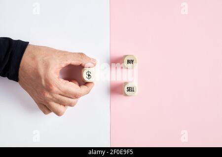 Männliche Hand hält einen Holzwürfel mit US-Dollar Währungssymbol zeigt auf die Optionen zu kaufen oder zu verkaufen. Kauf- oder Verkaufsentscheidung an der Börse oder dile Stockfoto