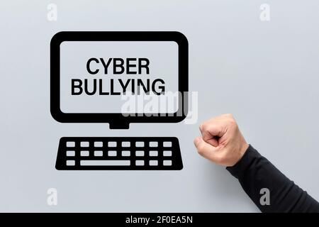 Männliche Faust mit einem Computer-Symbol mit Cyber-Mobbing auf dem Bildschirm geschrieben. Belästigung, Einschüchterung und Demütigung im Cyberraum. Stockfoto