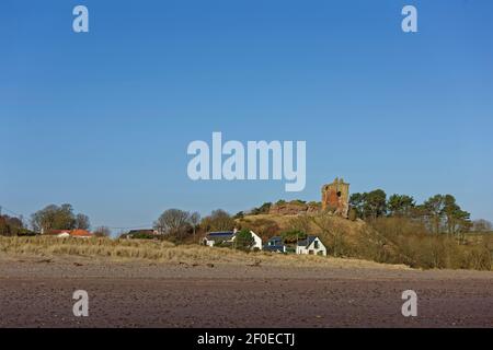 Eine kleine Ansammlung von Häusern am Lunan Wasser unterhalb der bröckelnden Überreste des Roten Schlosses auf einem Hügel über der Gemeinschaft. Stockfoto