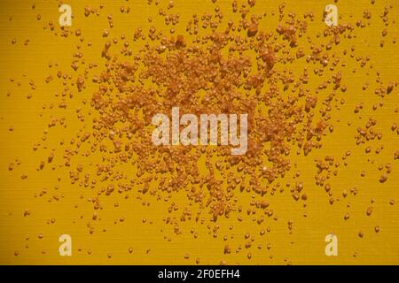 goldbraune Zuckerkristallwürfel auf gelbem Papierbogen-Hintergrund Stockfoto