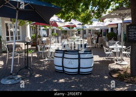 Dorfplatz mit Tischen im Freien des MCC Restaurant, Franschhoek, Western Cape Winelands, Western Cape, Südafrika mit Weinfass Dekor Stockfoto