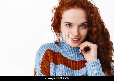 Haarpflege und Beauty-Konzept. Portrait von frechen attraktiven Rotschopf Frau mit natürlichen Ingwer lockiges Haar, Blick auf die Kamera kokett und zuversichtlich Stockfoto