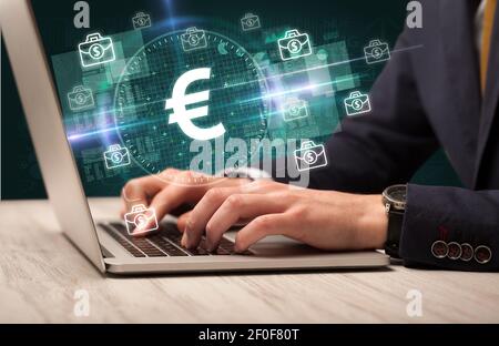 Business Hand arbeiten an der Börse mit Euro-Symbole kommen Aus dem Laptop-Bildschirm Stockfoto