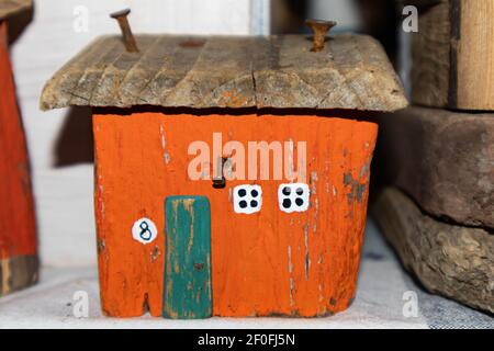 Altes orangefarbenes Holzhaus. Rostige Nägel werden ins Dach getrieben. Kleine weiße Fenster. Miniaturhütte Stockfoto