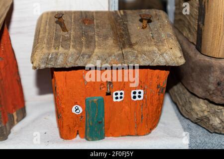 Altes orangefarbenes Holzhaus. Rostige Nägel werden ins Dach getrieben. Kleine weiße Fenster. Miniaturhütte Stockfoto