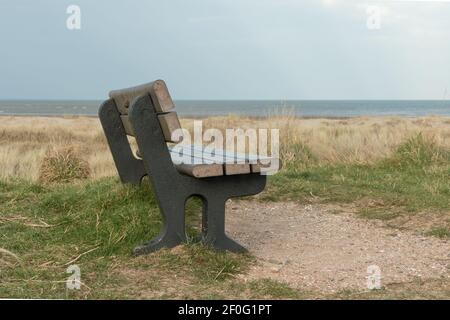 Ein Farbfoto eines Sitzes am Strand Raus über das Meer Stockfoto