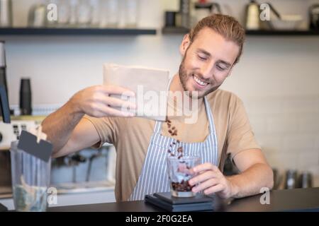 Mann in der Schürze glücklich Gießen Kaffeebohnen Stockfoto