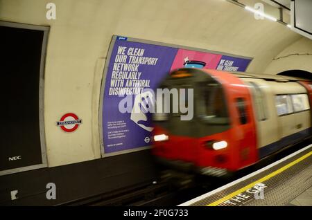 Passagiere und covid 19 Pandemie Gesicht Abdeckung und soziale Distanzierung Schilder auf die londoner U-Bahn-Züge 2021 Stockfoto