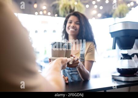 Fröhliche Frau, die Kaffee vom Barista nimmt Stockfoto