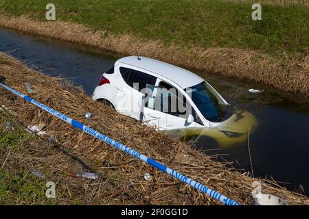 Rye, East Sussex, Großbritannien. März 2021, 7th. Der weiße Hyundai i10 stürzte durch eine hölzerne Einzäunungsmauer und landet halb in einem Wassergraben, der parallel zur Hauptstraße A259 zwischen Rye, East Sussex und Ashford, Kent verläuft. Foto-Kredit: Paul Lawrenson /Alamy Live Nachrichten Stockfoto