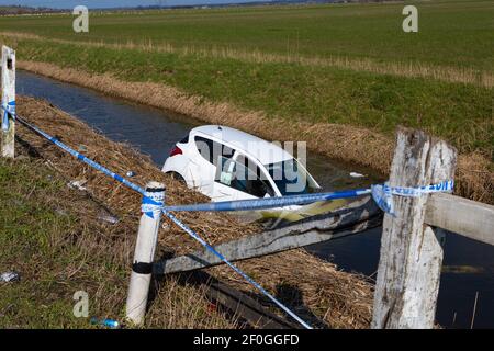 Rye, East Sussex, Großbritannien. März 2021, 7th. Der weiße Hyundai i10 stürzte durch eine hölzerne Einzäunungsmauer und landet halb in einem Wassergraben, der parallel zur Hauptstraße A259 zwischen Rye, East Sussex und Ashford, Kent verläuft. Foto-Kredit: Paul Lawrenson /Alamy Live Nachrichten Stockfoto