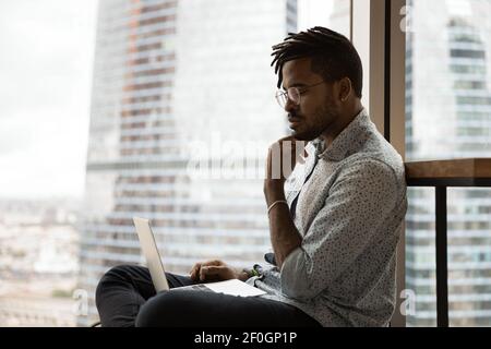 Seitenansicht nachdenklicher afroamerikanischer Mann beim Blick auf Laptop-Bildschirm Stockfoto