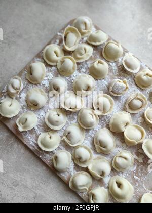 Traditionelle pelmeni oder Knödel auf Schneidebrett. Hausgemachte Zubereitung essen. Stockfoto