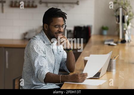 Nahaufnahme lächelnder afroamerikanischer Mann, der gute Nachrichten liest Stockfoto