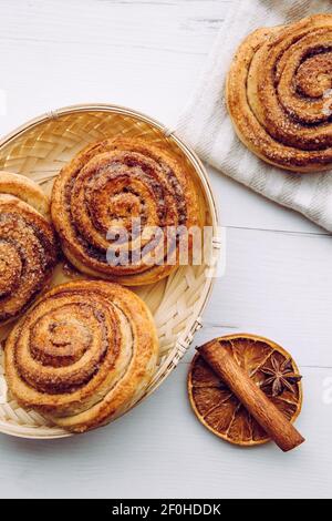 Frisch gebackene hausgemachte Zimtschnecken im Korb am Morgen drinnen, Frühstückskonzept. Stockfoto