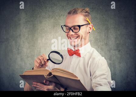 Portrait eines nerdy jungen Mannes, der ein altes Buch liest Stockfoto