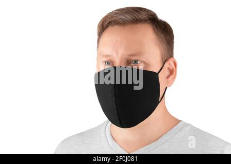 Ein junger kaukasischer Mann mit einem ordentlichen Haarschnitt, der eine schwarze Maske trägt, sieht zur Seite. Isoliert auf weiß, Seitenansicht. Nahaufnahme. Stockfoto