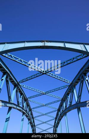 Niedrige Winkelansicht auf isoliertem symmetrischem Stahlbrückendeck Gegen blauen Himmel mit Kreuzstreben und Metallbalken Stockfoto