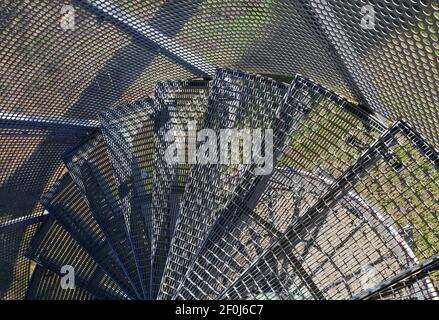 Blick nach unten auf schmale enge steile Wendeltreppe aus Stahl im Freien Mit Stufen aus Metallgitter - Deutschland Stockfoto