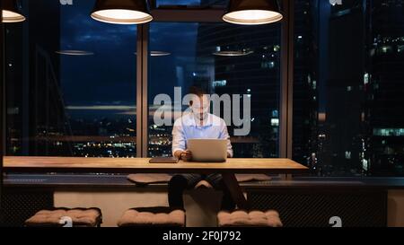 Afroamerikanischer Geschäftsmann, der nachts im Büro am Laptop arbeitet Stockfoto