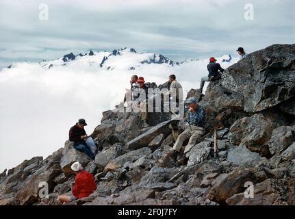 Dia / Umkehrfilm einer Gruppe von Menschen, die auf einem felsigen Berg sitzen. Diese wurde im August 1960 aufgenommen. Stockfoto