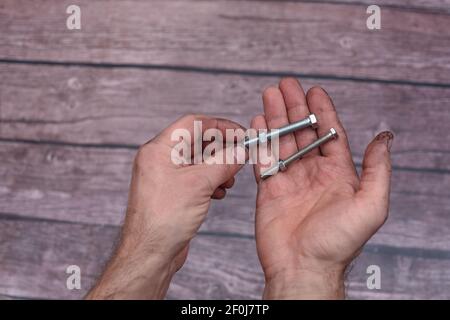 Schrauben mit Muttern in den Händen. Hände des Mechanikers. Stockfoto