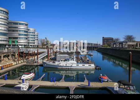 Duisburg (innenhafen), Deutschland - März 1. 2021: Blick über die Marina auf moderne silberne Bürogebäude (fünf Boote) gegen blauen Himmel Stockfoto