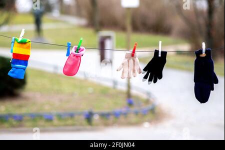 Braunschweig, Deutschland. März 2021, 07th. Einzelne Handschuhe, die von Spaziergängern im Museumspark verloren gegangen sind, werden mit Wäscheklammern an einer Linie nahe dem Staatstheater in der Innenstadt aufgehängt. Dies gibt Besitzern die Möglichkeit, ihren verlorenen Handschuh leichter zu finden. Quelle: Hauke-Christian Dittrich/dpa/Alamy Live News Stockfoto