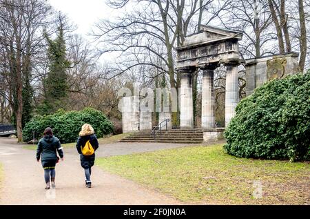 Braunschweig, Deutschland. März 2021, 07th. Zwei Frauen laufen am historischen Portikus im Bürgerpark vorbei. Der Portikus wurde 1896 absichtlich als Ruine im Park entworfen, wurde aber im Zweiten Weltkrieg beschädigt und bleibt bis heute unverändert. Quelle: Hauke-Christian Dittrich/dpa/Alamy Live News Stockfoto