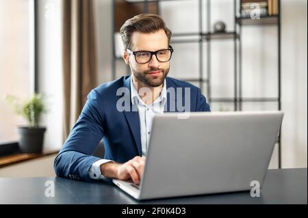 Entspannter Mann arbeitet im modernen Büro, tippen auf der Tastatur, sitzen auf bequemen Stuhl, fühlt sich Gelassenheit, genießen Sie frische Klimaanlage, kein Stress, Müdigkeit lindern am Arbeitsplatz Konzept, tolle Atmosphäre Stockfoto