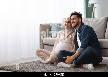 Glückliche islamische Ehegatten erwarten EIN Baby, das zusammen zu Hause ruht Stockfoto