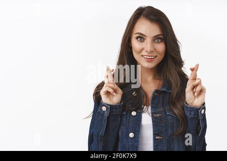 Hoffnungsvoll niedlich kaukasischen Weibchen mit blauen Augen, modischen Look, Kreuzfinger viel Glück, stehen in der Nähe klar, leeren weißen Raum, beten, wollen Stockfoto