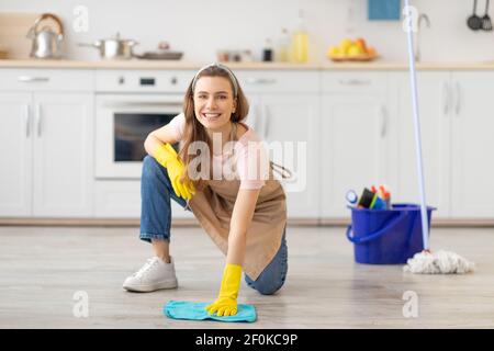 Haushaltung Konzept. Glückliche junge Frau wischen Boden in der Küche, tragen Gummihandschuhe, mit Reinigungsmitteln Stockfoto