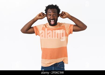 Glücklich, sorglos bärtig afroamerikanischen Kerl Spaß, keine Angst, lustig und niedlich, zeigt urkomische Gesichter, Grimacing spielerisch, Ziehen Ohren Stockfoto