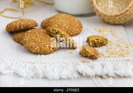 Sesamkekse auf einem weißen Teller, Sesamsamen in einem Weidenkorb, raue gewebte Tischdecke, flache Laie, Kopierraum Stockfoto