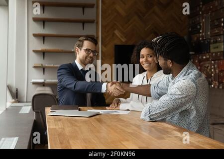 Lächelnd kaukasischen makler und afroamerikanische Familie Händeschütteln Stockfoto