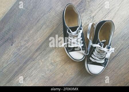 Schwarz-weiße Sneaker auf Holzboden. Speicherplatz kopieren. Stockfoto