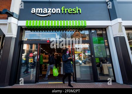 London, Großbritannien. 7. März 2021. Kunden verlassen am ersten Eröffnungswochenende den neuen 2.500 Quadratmeter großen Amazon Fresh Store in Ealing, West London. Es ist der erste "Just Walk Out" Lebensmittelgeschäft in Großbritannien und der erste außerhalb der USA. Als „kontaktloser“ Shop steht er allen bei Amazon angemeldeten und mit der App auf ihrem Smartphone zur Verfügung. In-Store-Kameras und künstliche Intelligenz überwachen Kunden, die Artikel abholen, die einfach gehen und die Abrechnung erfolgt später automatisch. Kredit: Stephen Chung / Alamy Live Nachrichten Stockfoto