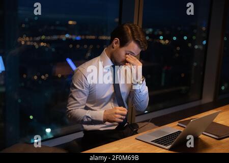 Nahaufnahme erschöpfter Geschäftsmann, der die Brille auszieht und nachts arbeitet Stockfoto