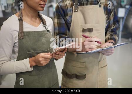 Zugeschnittenes Porträt von zwei jungen Arbeitern mit digitalen Tablet während der Überwachung der Produktion in modernen Craft Brauerei, Copy Space Stockfoto