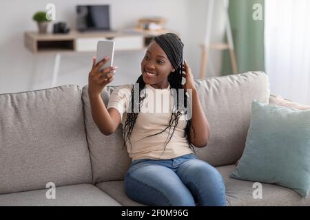 Nette junge schwarze Dame, die Selfie auf dem Smartphone nimmt Stockfoto