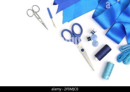 Kreative Komposition mit blauen Nähwerkzeugen und Accessoires in weißem Rahmen mit Schere, Spulen aus Fäden und blauem Stoff Ribbo geschnitten und isoliert Stockfoto